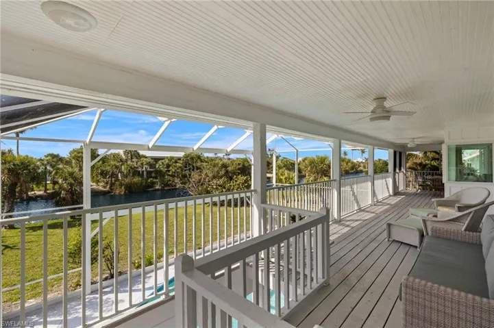 Deck with ceiling fan, a water view, a sunroom, a lanai, and a lawn