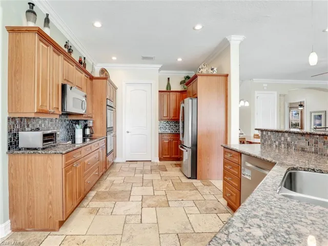 Kitchen featuring backsplash, appliances with stainless steel finishes, and light tile floors