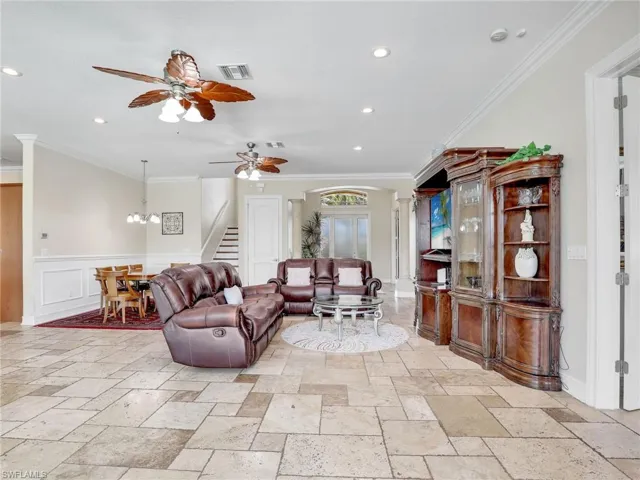 Living room with ceiling fan, crown molding, and light tile floors