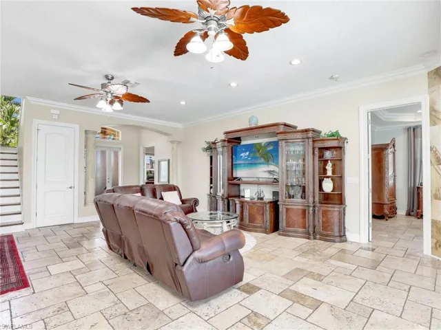 Living room with crown molding, light tile flooring, and ceiling fan