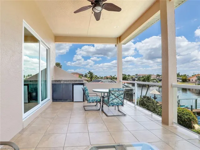 View of terrace with ceiling fan, a balcony, and a water view