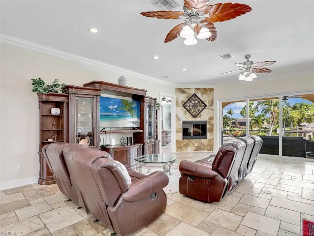 Tiled living room featuring ceiling fan, a fireplace, and ornamental molding