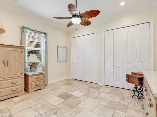 Bedroom featuring two closets, ceiling fan, ornamental molding, and light tile floors