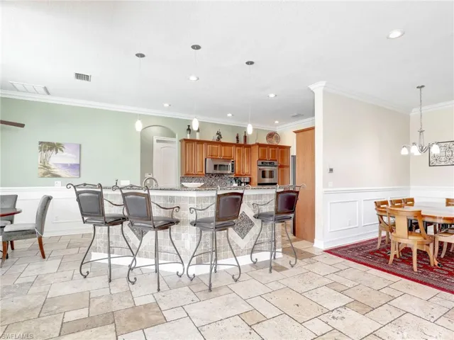 Kitchen featuring a kitchen breakfast bar, ornamental molding, light tile floors, and appliances with stainless steel finishes