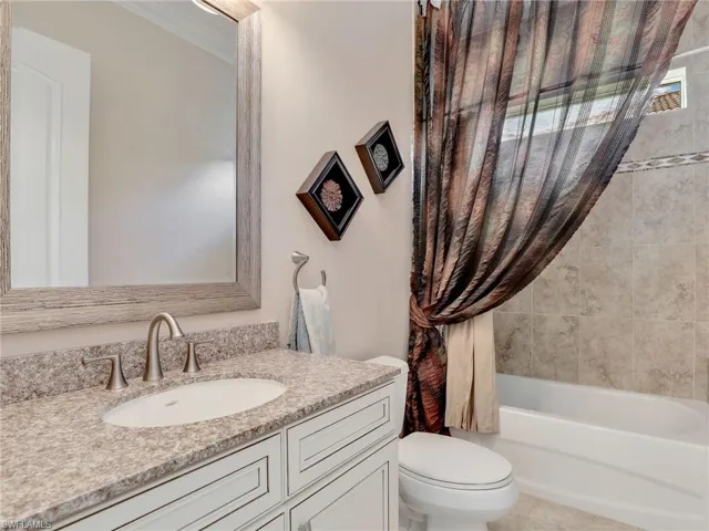 Full bathroom featuring tile floors, vanity, toilet, and shower / bath combo with shower curtain