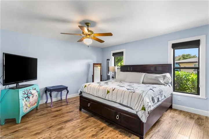 Bedroom featuring ceiling fan, multiple windows, and hardwood / wood-style flooring