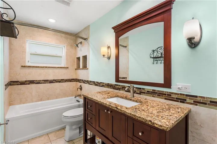 Full bathroom featuring vanity, washtub / shower combination, tile patterned flooring, and toilet