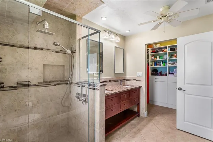 Bathroom featuring vanity, an enclosed shower, ceiling fan, and tile patterned floors