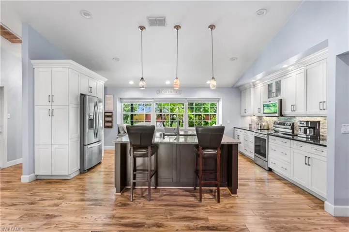 Kitchen featuring backsplash, a kitchen bar, light wood-type flooring, and stainless steel appliances