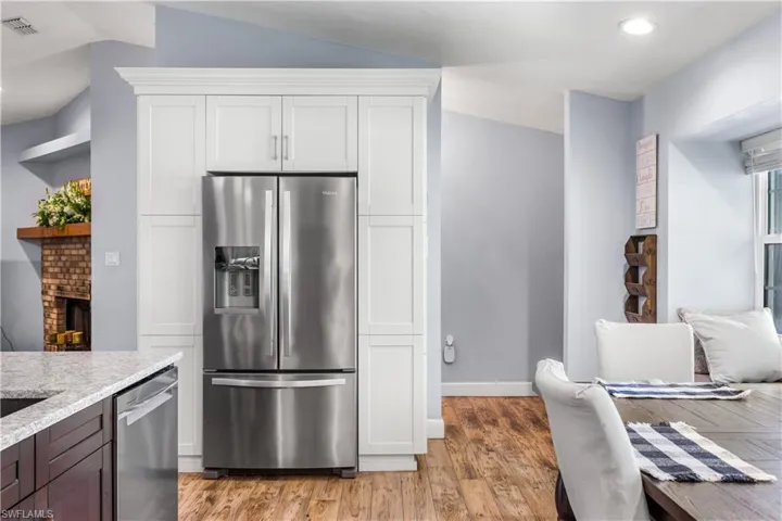 Kitchen with white cabinetry, vaulted ceiling, appliances with stainless steel finishes, and light wood-type flooring
