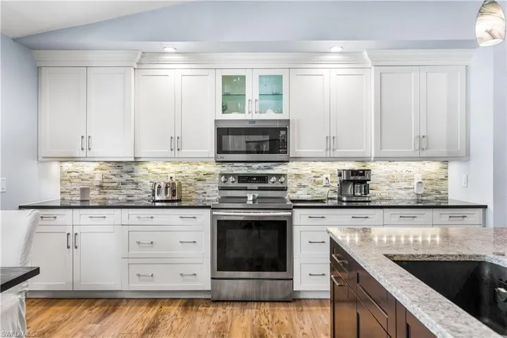 Kitchen featuring light wood-type flooring, tasteful backsplash, and stainless steel appliances