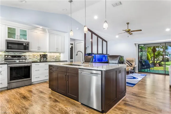 Kitchen featuring stainless steel appliances, vaulted ceiling, sink, backsplash, and light hardwood / wood-style floors
