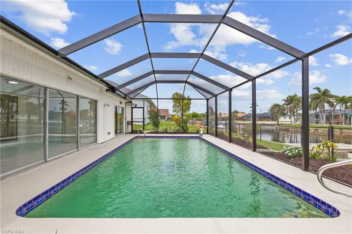 Pool with a screened lanai, a water view, and a patio area