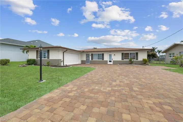 Single story home featuring stucco siding, fence, decorative paver driveway, and a garage