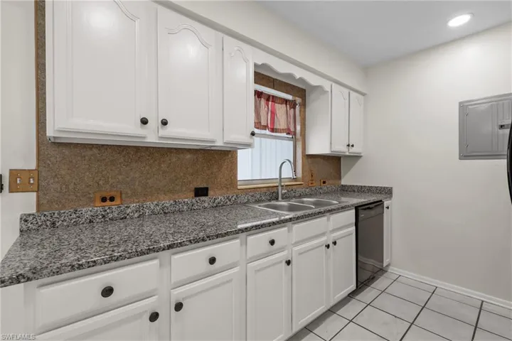 3/3 Side: Kitchen featuring white cabinetry, dishwasher, a sink, and granite counter tops.