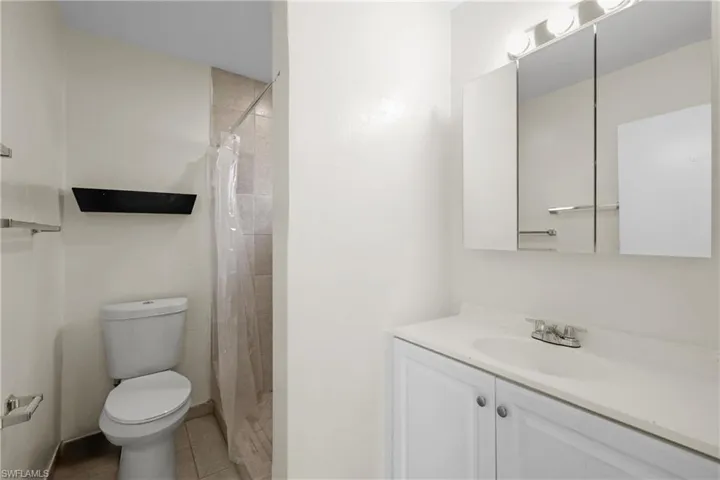 3/3 Side: Bathroom featuring toilet, vanity, tile flooring, and a tile shower