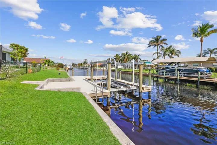 View of dock and canal with a 10000 lb boat lift and wrap around deck.