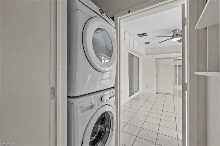 Shared stacked washer / dryer, laundry area, a ceiling fan, and light tile floors