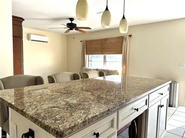 1/1 Side: Kitchen featuring a kitchen breakfast bar, white cabinets, granite counters, and a wall mounted air conditioner