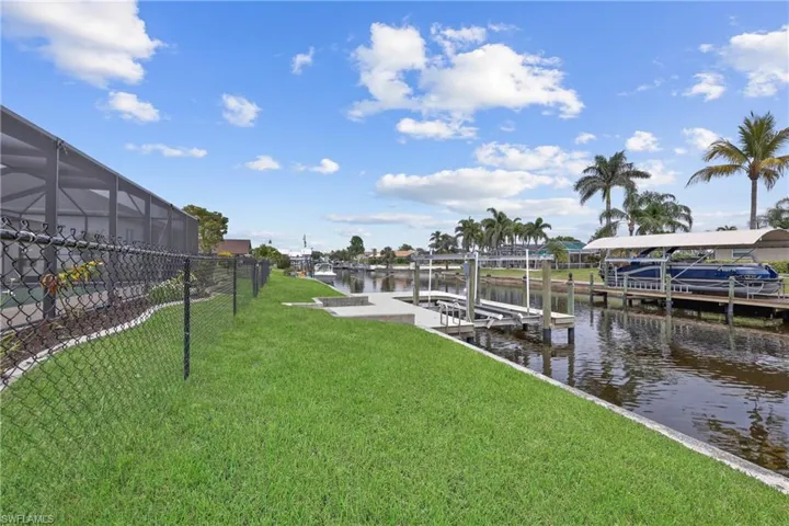 Dock area with fenced backyard, 10000 lb boat lift, a water view, and a yard