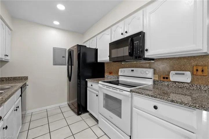 3/3 Side: Kitchen featuring white cabinetry, light tile floors, backsplash, granite counter tops, and appliances