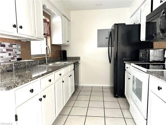 Kitchen with light tile flooring, sink, white cabinetry, and black appliances
