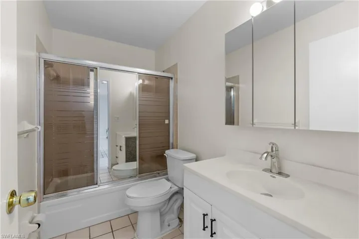 3/3 Side Full bath featuring toilet, tile flooring, vanity, and enclosed tub / shower combo
