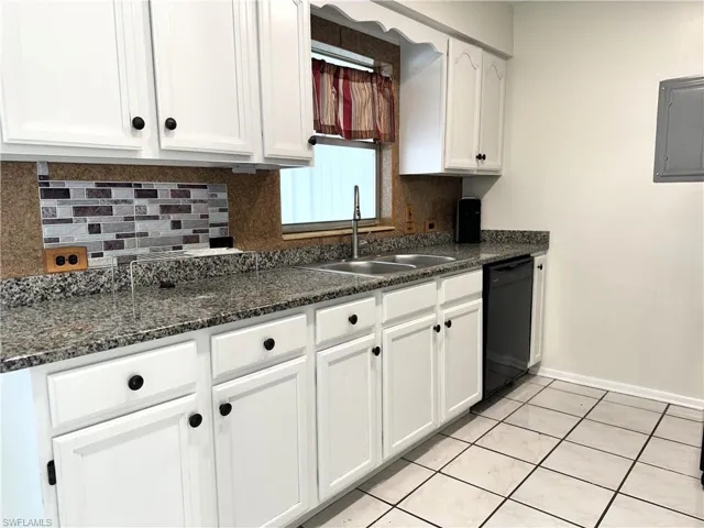 Kitchen with white cabinetry, sink, black dishwasher, backsplash, and light tile floors