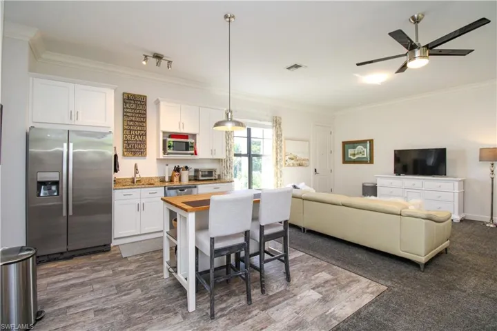 Kitchen with wood counters, appliances with stainless steel finishes, crown molding, pendant lighting, and white cabinets