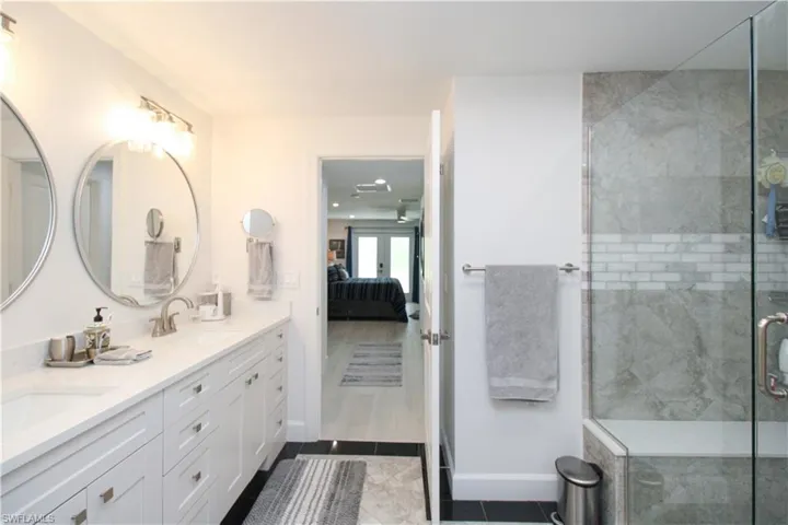 Bathroom with french doors, vanity, tile patterned floors, and a shower with door
