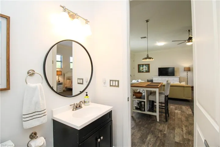 Bathroom featuring hardwood / wood-style floors, ceiling fan, ornamental molding, and vanity