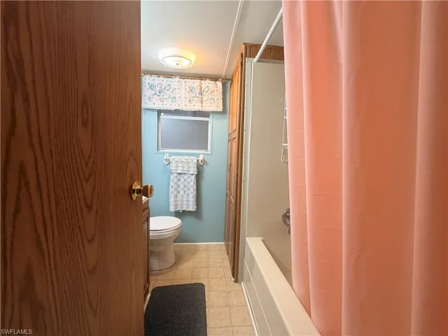 Bathroom featuring shower / bathtub combination with curtain and light floors