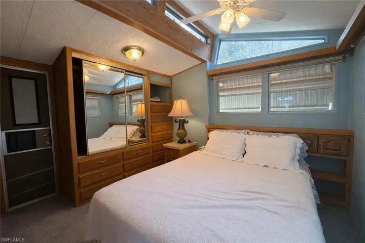 Carpeted bedroom featuring vaulted ceiling, a closet, a textured ceiling, and ceiling fan