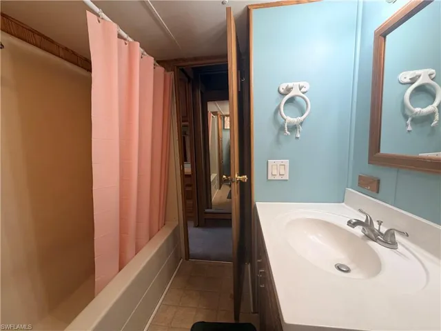 Bathroom featuring vanity, shower / tub combo with curtain, and light tile patterned floors
