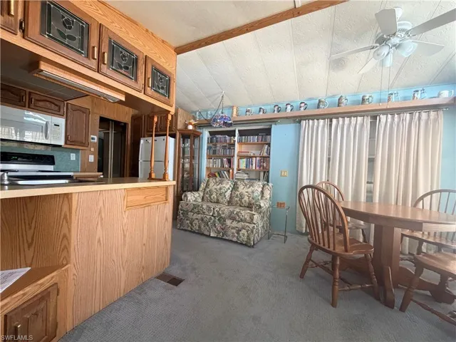 Kitchen featuring stainless steel appliances, dark carpet, a ceiling fan, and a textured ceiling