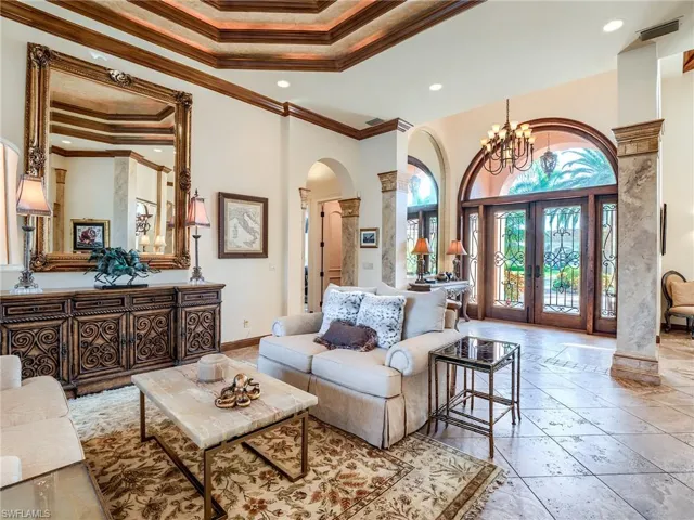 Living room with a tray ceiling, ornate columns, and ornamental molding