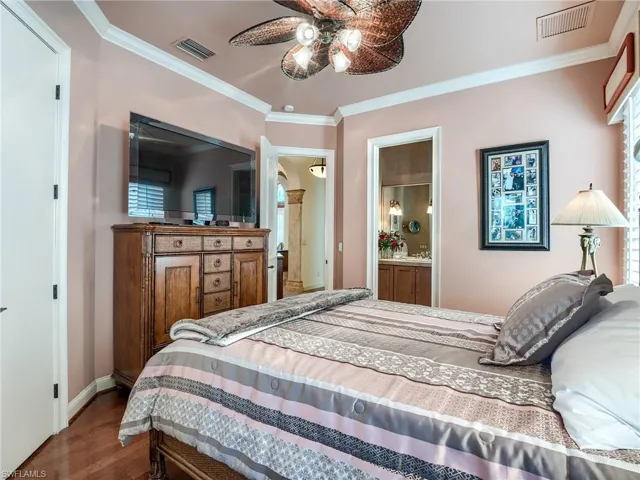 Bedroom with ceiling fan, multiple windows, crown molding, hardwood / wood-style flooring, and connected bathroom
