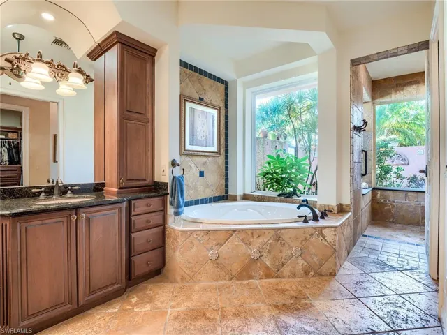 Bathroom with tiled bath, tile patterned floors, vanity, and a wealth of natural light