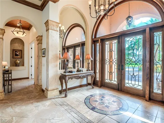 Foyer with french doors, crown molding, a chandelier, light tile patterned floors, and a towering ceiling