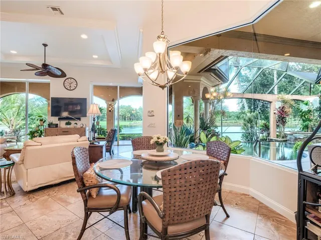 Dining space featuring light tile patterned floors, a raised ceiling, and ceiling fan with notable chandelier