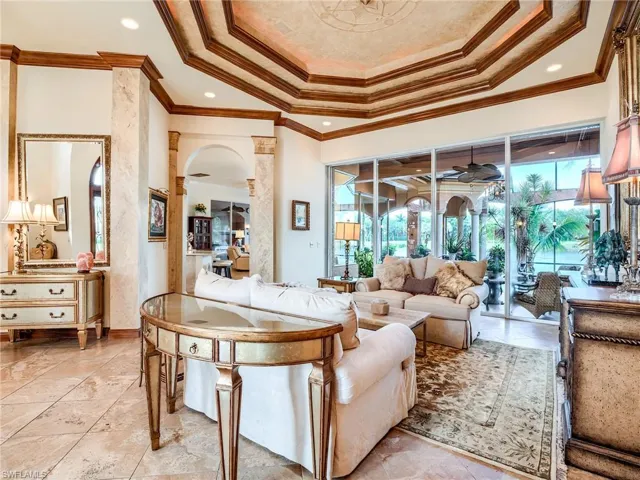 Tiled living room with ceiling fan, a raised ceiling, and ornamental molding