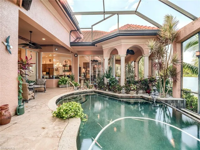 View of swimming pool with glass enclosure, ceiling fan, and a patio