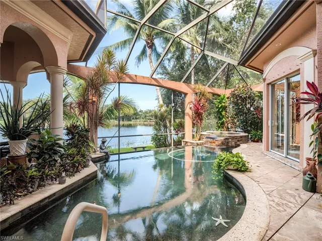 View of swimming pool featuring glass enclosure, a water view, and an in ground hot tub