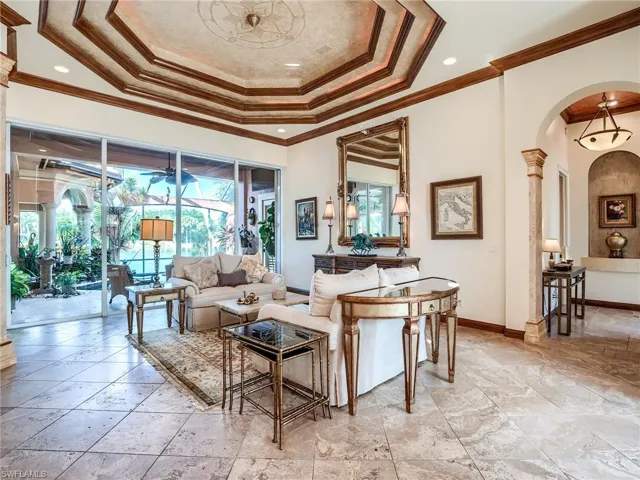 Tiled living room featuring a wealth of natural light, ornamental molding, and a tray ceiling