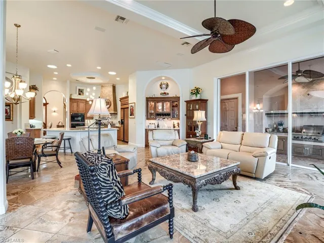 Tiled living room featuring ceiling fan with notable chandelier