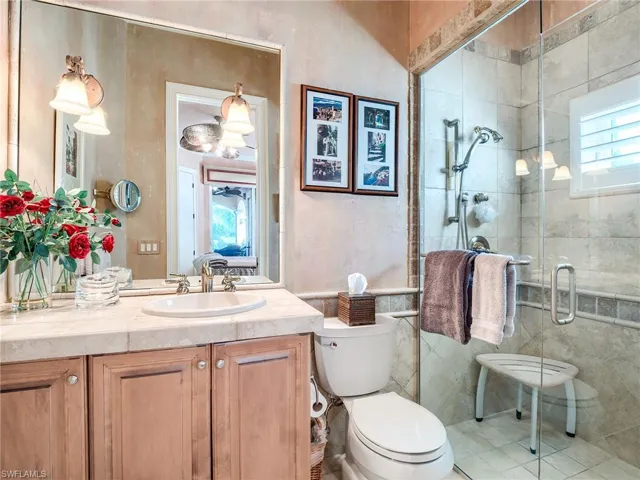 Bathroom featuring a shower with shower door, vanity, toilet, and tile patterned flooring