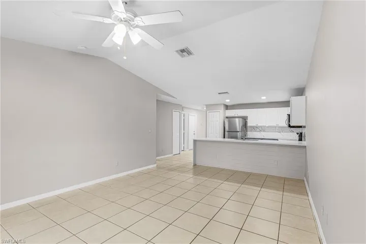Unfurnished living room with light tile patterned floors, ceiling fan, vaulted ceiling, and recessed lighting