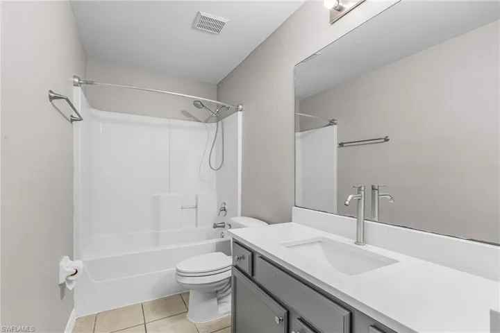 Full bath with vanity, light tile patterned flooring, and bathtub / shower combination