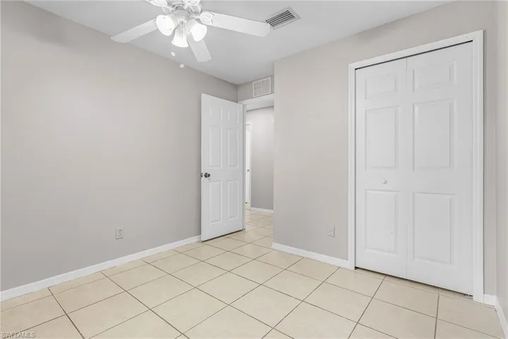 Unfurnished bedroom with light tile patterned floors, a ceiling fan, and a closet