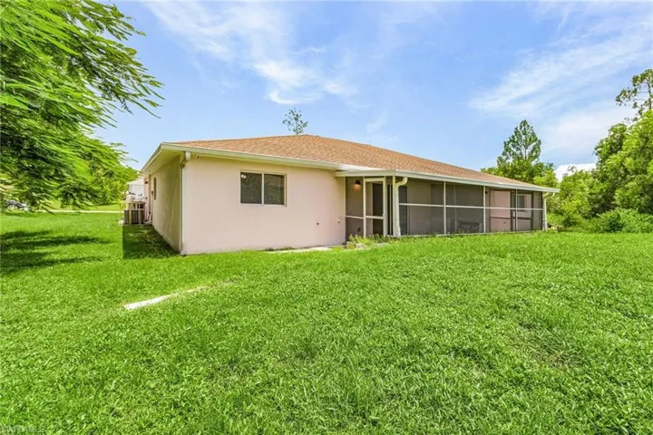Back of house with a sunroom, a yard, and stucco siding